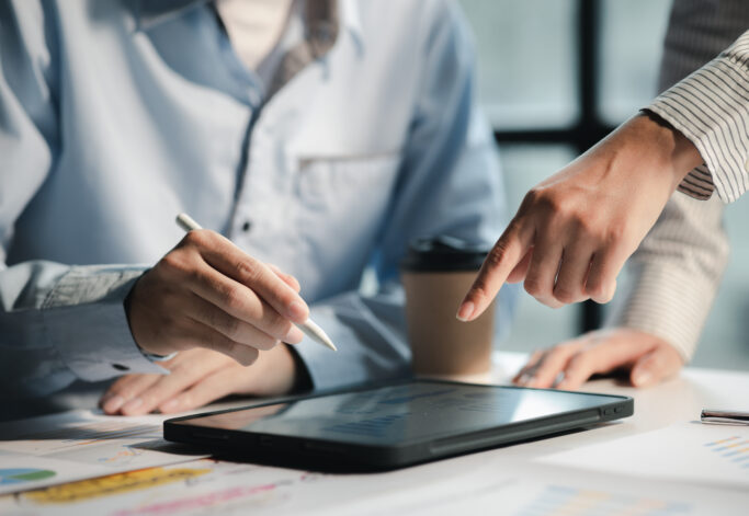 A meeting of two businessmen brainstorming a marketing plan and analyzing sales to come up with strategies for marketing to increase the company's sales. Business administration concept.